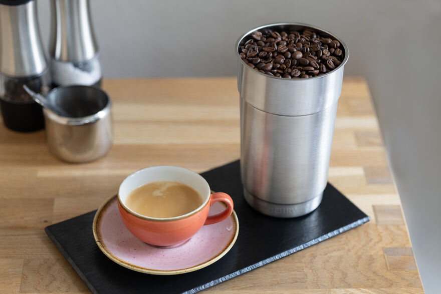 Espresso in Tasse neben hohem Behälter mit Kaffeebohnen