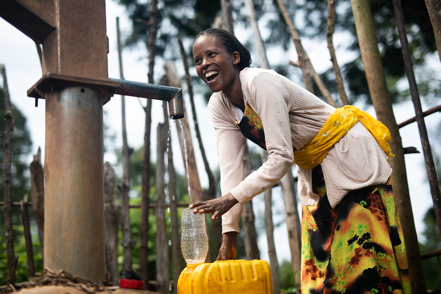 Eine Frau füllt einen Wasserkanister an einer Wasserpumpe auf