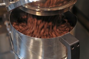 Link: Großansicht des Bildes - Bildinhalt: Eine Nahaufnahme von Kaffeebohnen, die in einen runden, silbernen Metallbehälter rieseln.