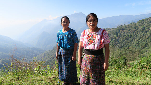 Zwei Frauen in Tracht vor grünem Bergpanorama