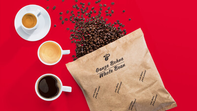 Kaffeebohnen und drei Tassen Kaffee auf Rot