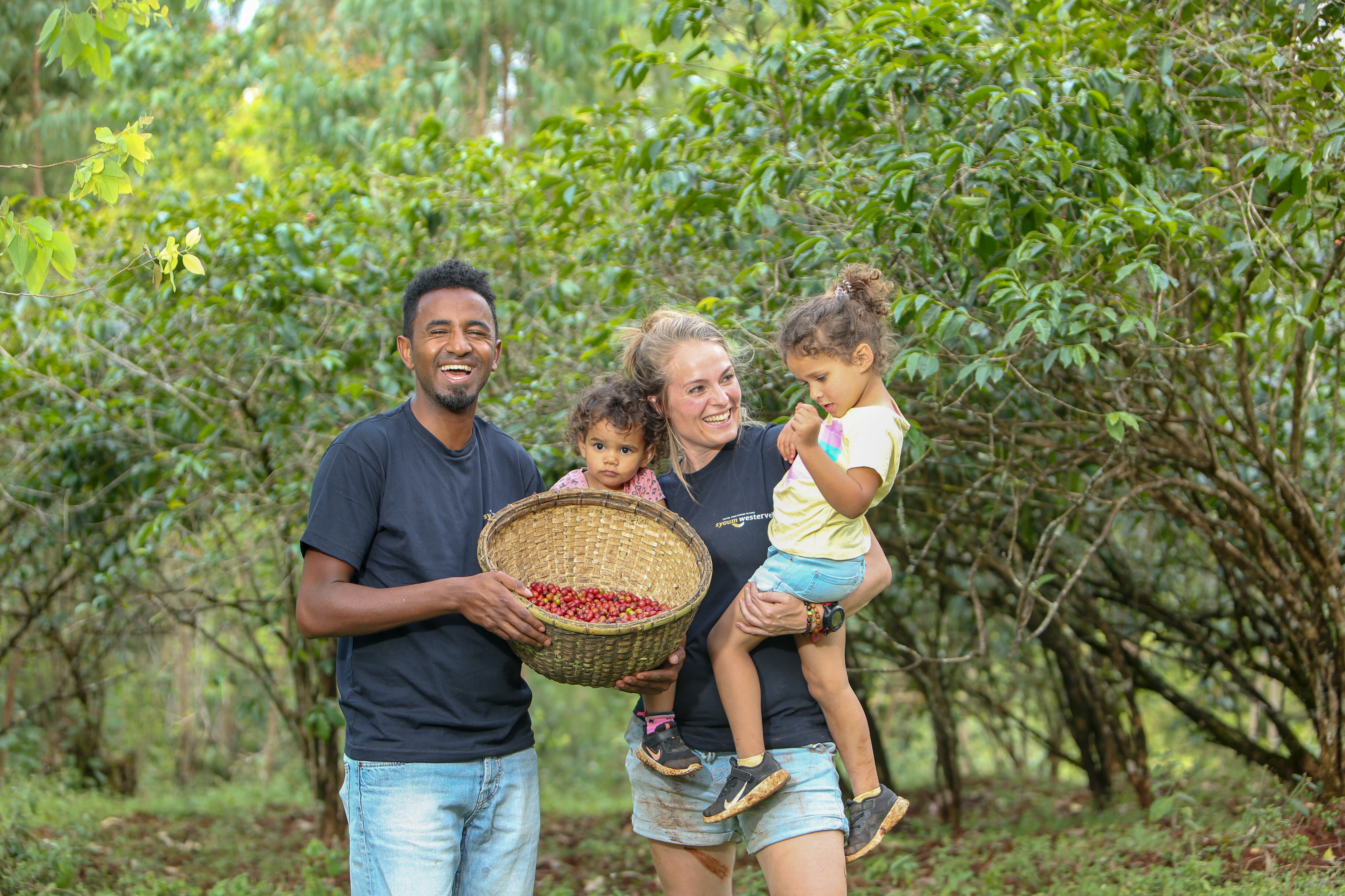 Familie mit Korb roter Kaffeekirschen im Wald