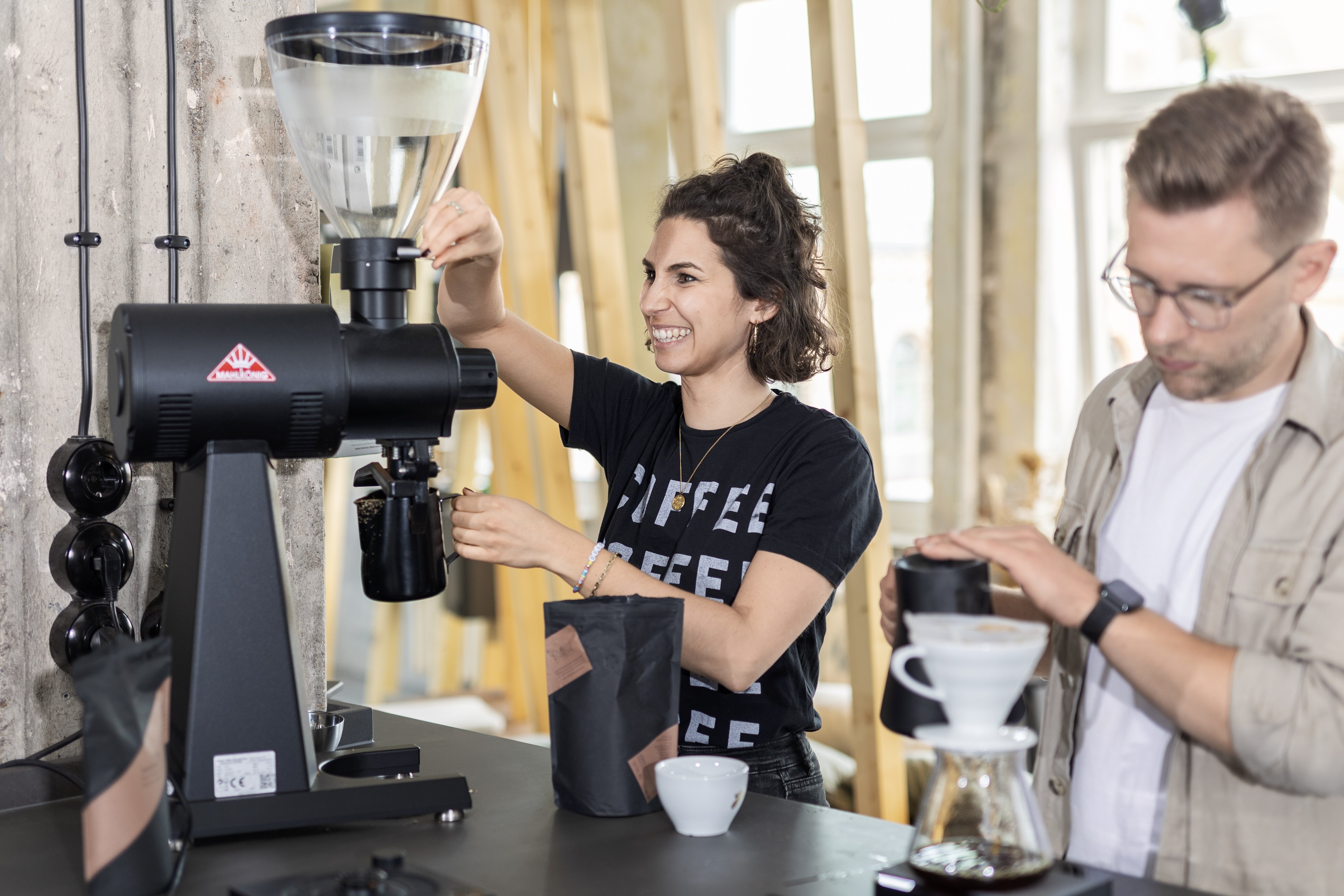 Zwei Personen mahlen und brühen Kaffee in Baristaecke