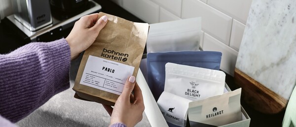 Hände halten Kaffeepackung neben Box mit weiteren Sorten