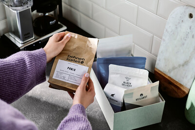 Person hält Kaffeepackung vor Box mit weiteren Sorten