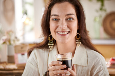 Person hält ein Glas schwarzen Kaffee