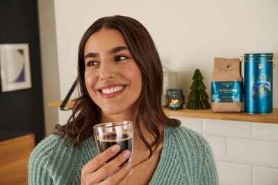 Person mit Kaffeglas vor weihnachtlicher Deko
