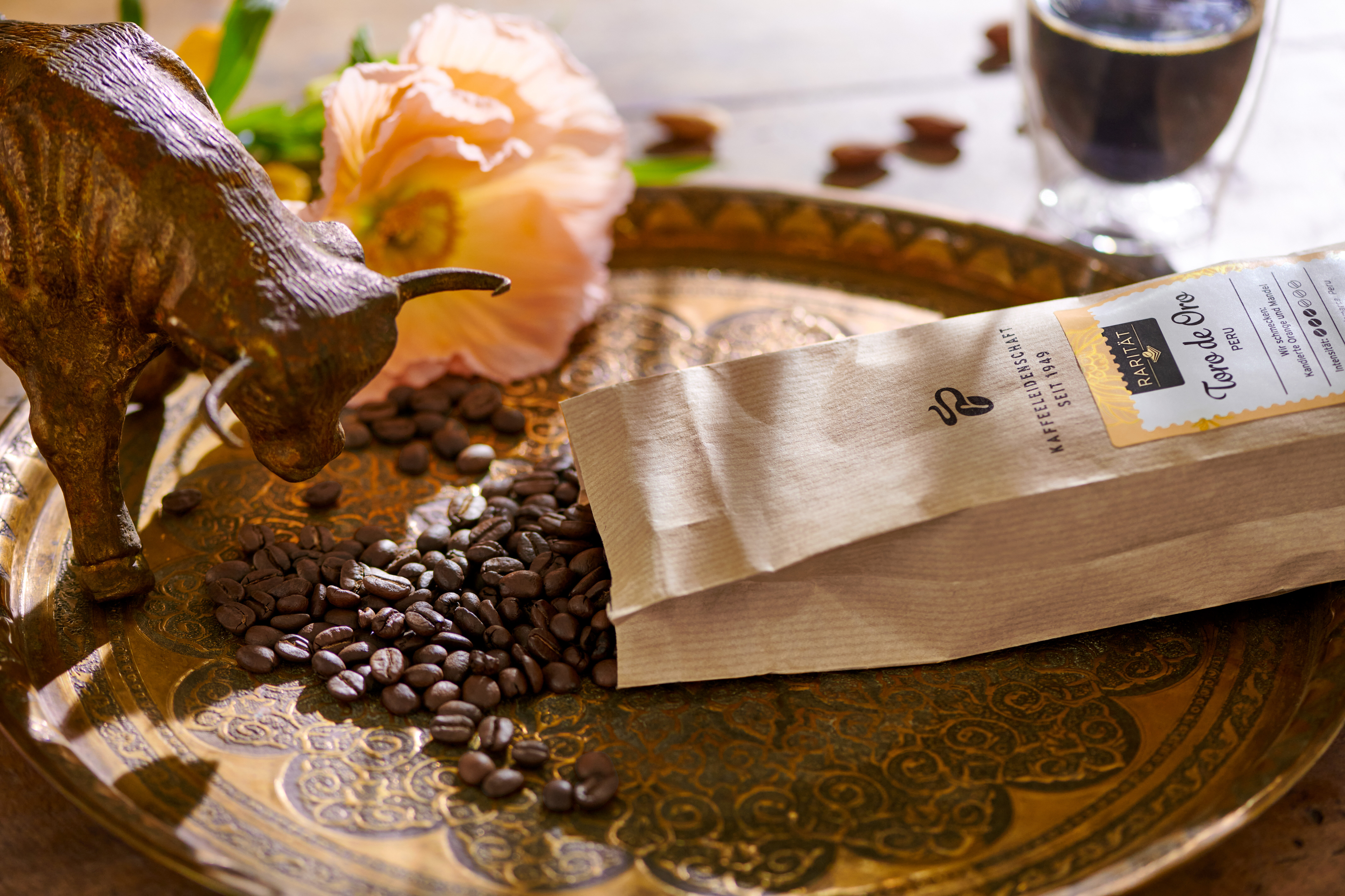 Kaffeebohnen, Tüte, Stierfigur und Blume auf Tablett