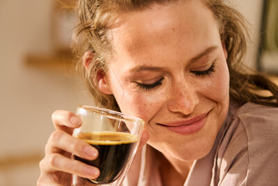Person hält Glas mit schwarzem Kaffee
