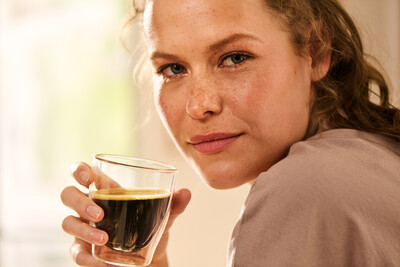 Hand hält ein Glas mit schwarzem Kaffee