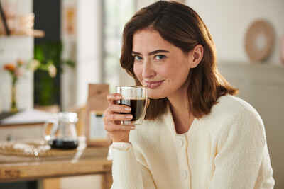 Person in heller Strickjacke trinkt Kaffee