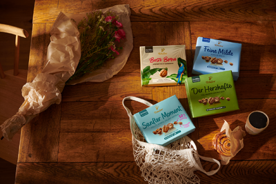 Kaffeepackungen, Blumenstrauß und Gebäck auf Holztisch