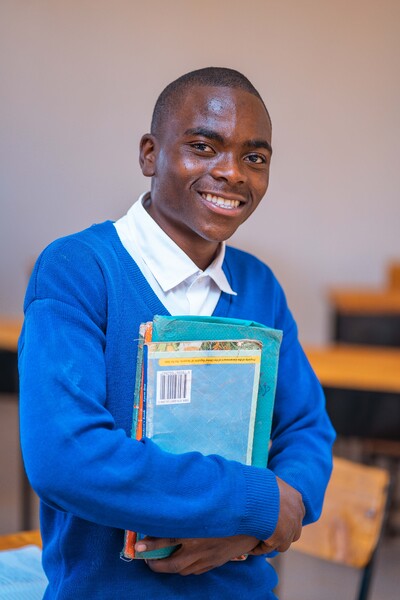 Schüler in blauer Uniform hält Schulbücher