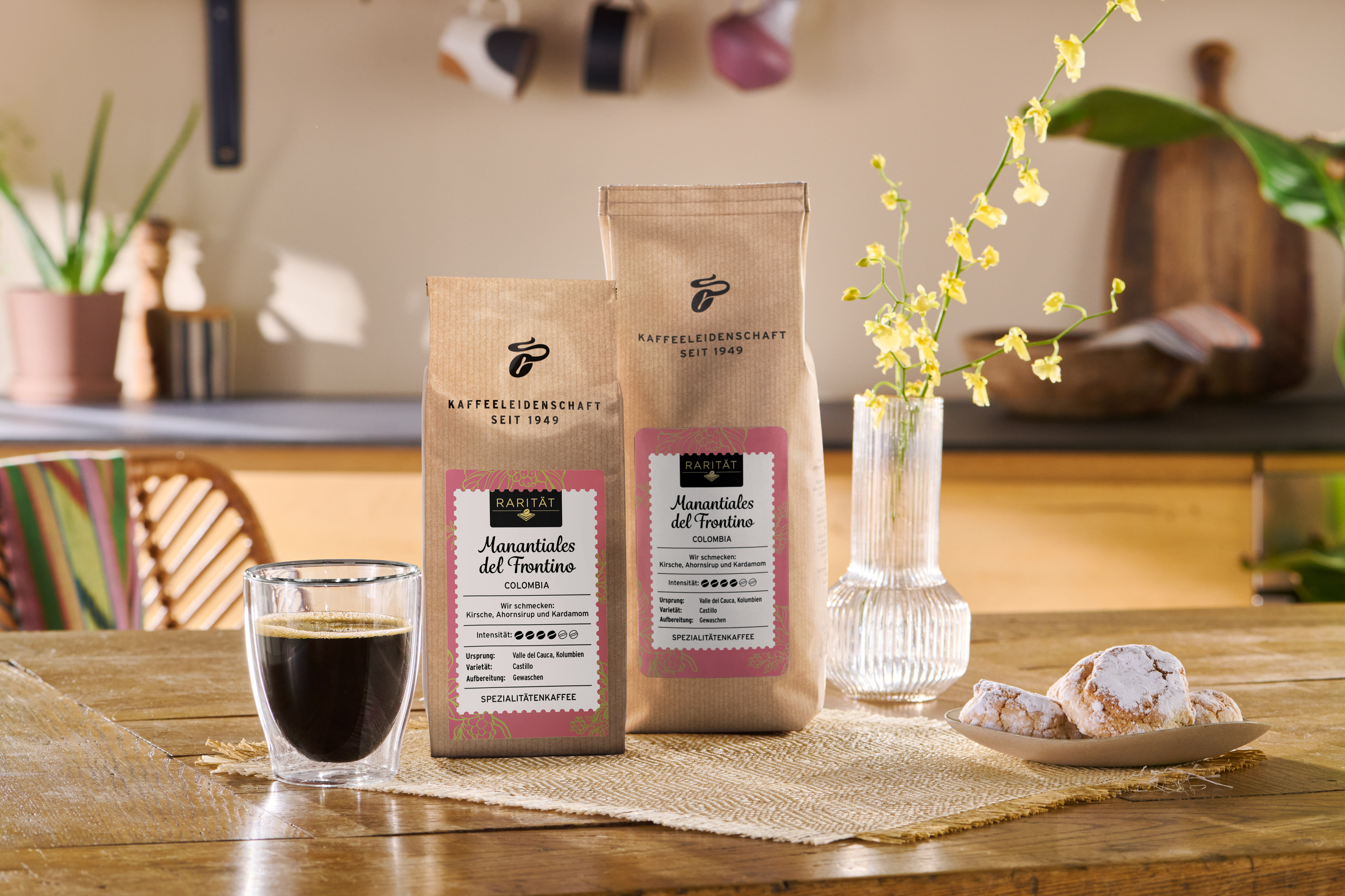 Kaffeepackungen mit Glas Kaffee und Gebäck auf Tisch