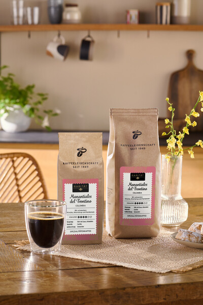 Zwei Kaffeepackungen mit Glas Kaffee auf Holztisch