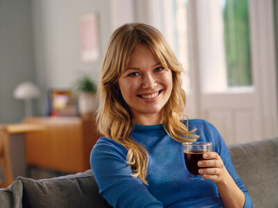 Lächelnde Frau auf Sofa mit Glas Kaffee