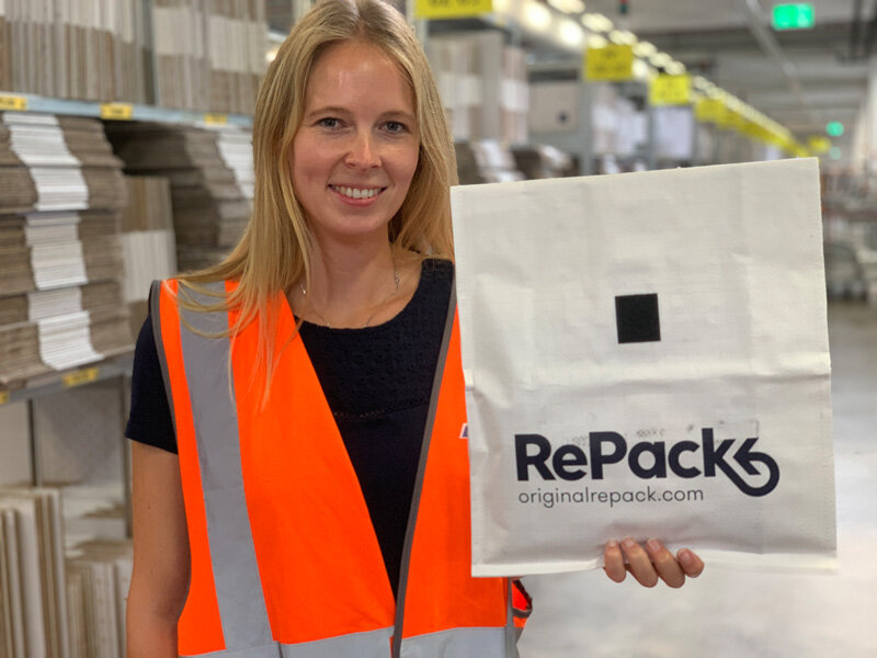 Frau im Lager hält weiße RePack-Tasche hoch