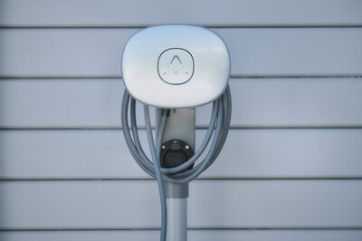 Weiße E-Auto-Ladestation mit aufgewickeltem Kabel