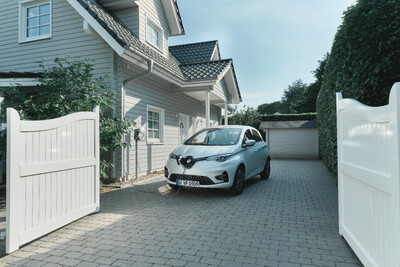 Elektroauto lädt in Auffahrt vor Einfamilienhaus