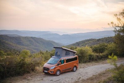 Oranger Campervan mit Aufstelldach in Berglandschaft