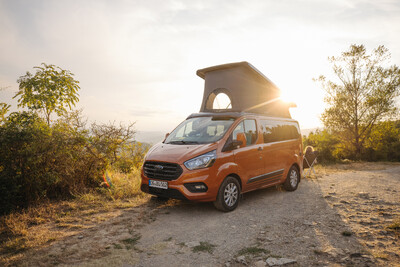 Orange Campervan mit Aufstelldach bei Sonnenuntergang