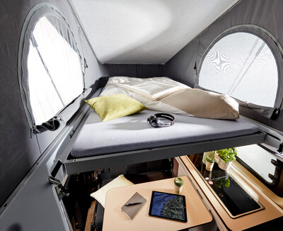 Kompaktes Camper-Interieur mit Bett und kleinem Arbeitsplatz