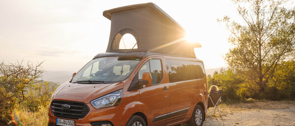 Orangefarbener Campervan im Sonnenuntergang