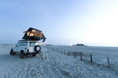 Geländewagen mit Dachzelt am einsamen Strand
