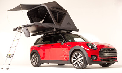 Rotes Auto mit Dachzelt und Anstellleiter