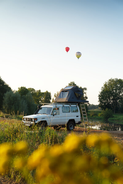 Geländewagen mit Dachzelt, zwei Heißluftballons