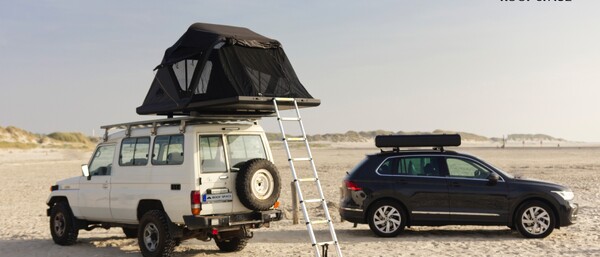 Zwei Autos am Strand mit Dachzelt und Leiter