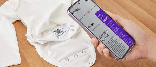 Hand scannt QR-Code an weißem Babybody mit Handy