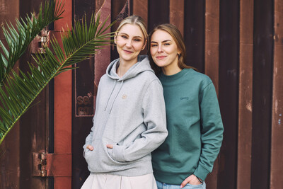 Zwei Personen in Hoodies vor rostiger Wand