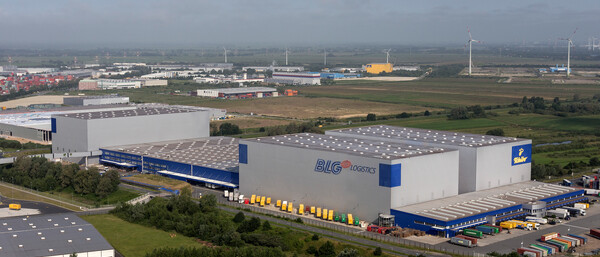 Großes Logistikzentrum mit Lkw und Windrädern