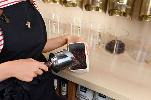 Person füllt Kaffeebohnen in einen Behälter