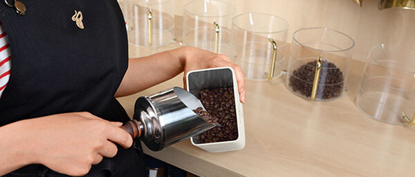 Person füllt Kaffeebohnen in einen Behälter