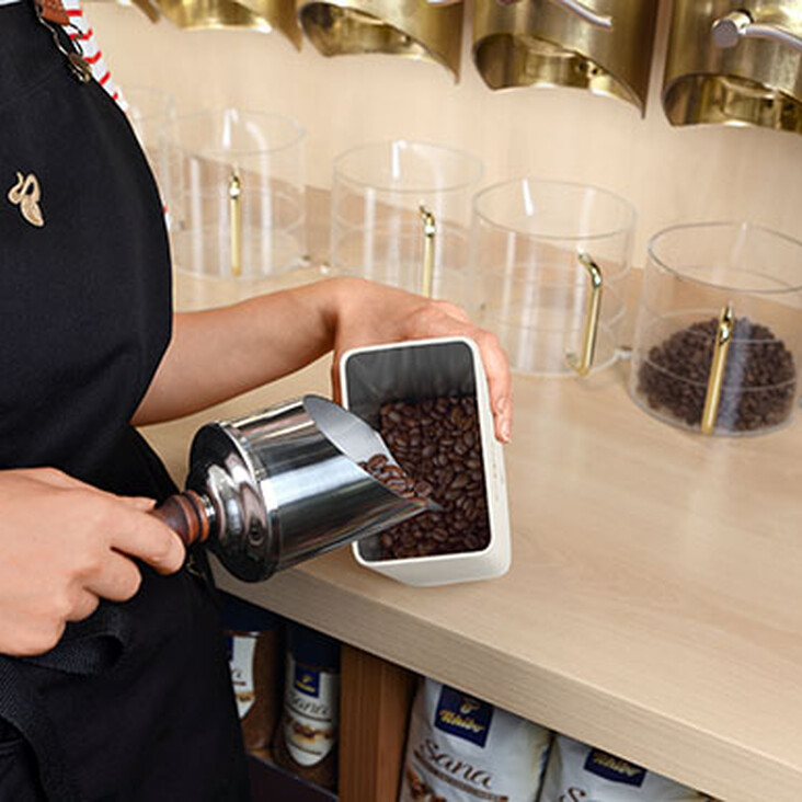 Person füllt Kaffeebohnen in einen Behälter