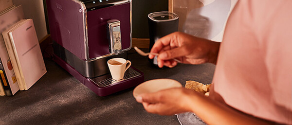 Person bereitet Kaffee an lila Maschine zu