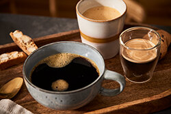 Drei Tassen Kaffee auf Holztablett mit Gebäck