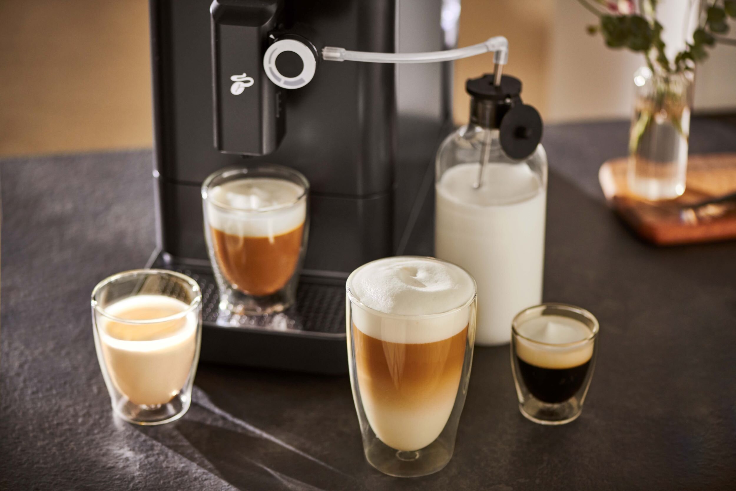 Kaffeemaschine mit vier Latte-Gläsern und Milchkaraffe