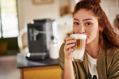 Person trinkt Latte Macchiato in Küche