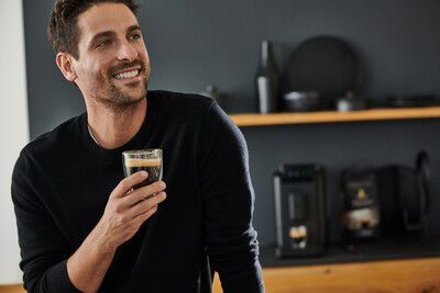 Person hält Glas Kaffee in moderner Küche