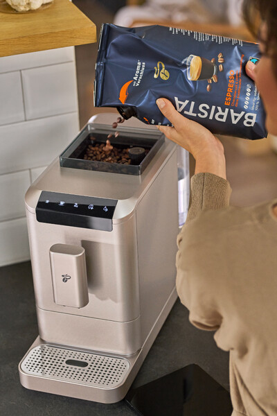 Person füllt Espressobohnen in Kaffeemaschine
