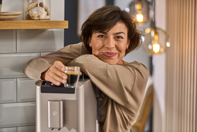 Person lehnt an Kaffeemaschine mit Espresso