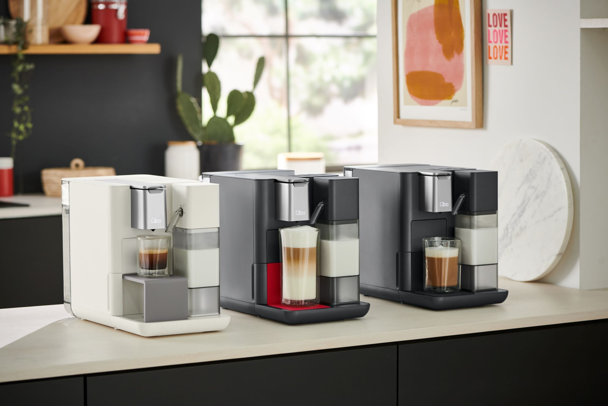 Drei moderne Kaffeemaschinen mit Latte Macchiato