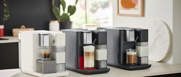 Drei moderne Kaffeemaschinen mit Latte Macchiato