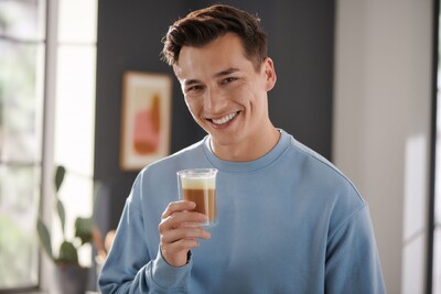 Person im blauen Pulli hält Latte Macchiato
