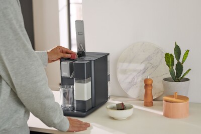 Person bedient Kapsel-Kaffeemaschine in Küche