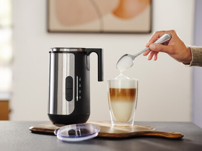 Hand löffelt Milchschaum in Latte Macchiato