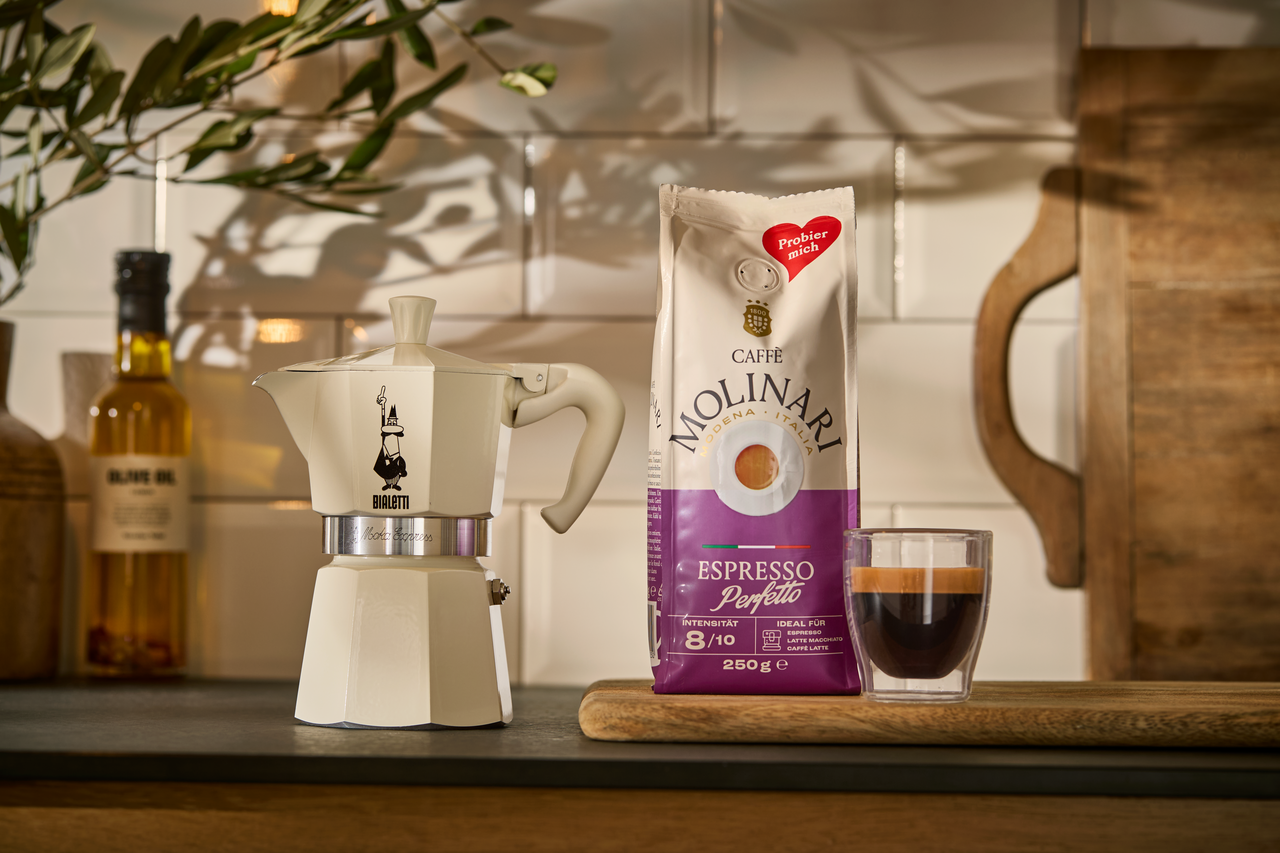 Espressomaschine, Kaffeepackung und Glas auf Arbeitsplatte